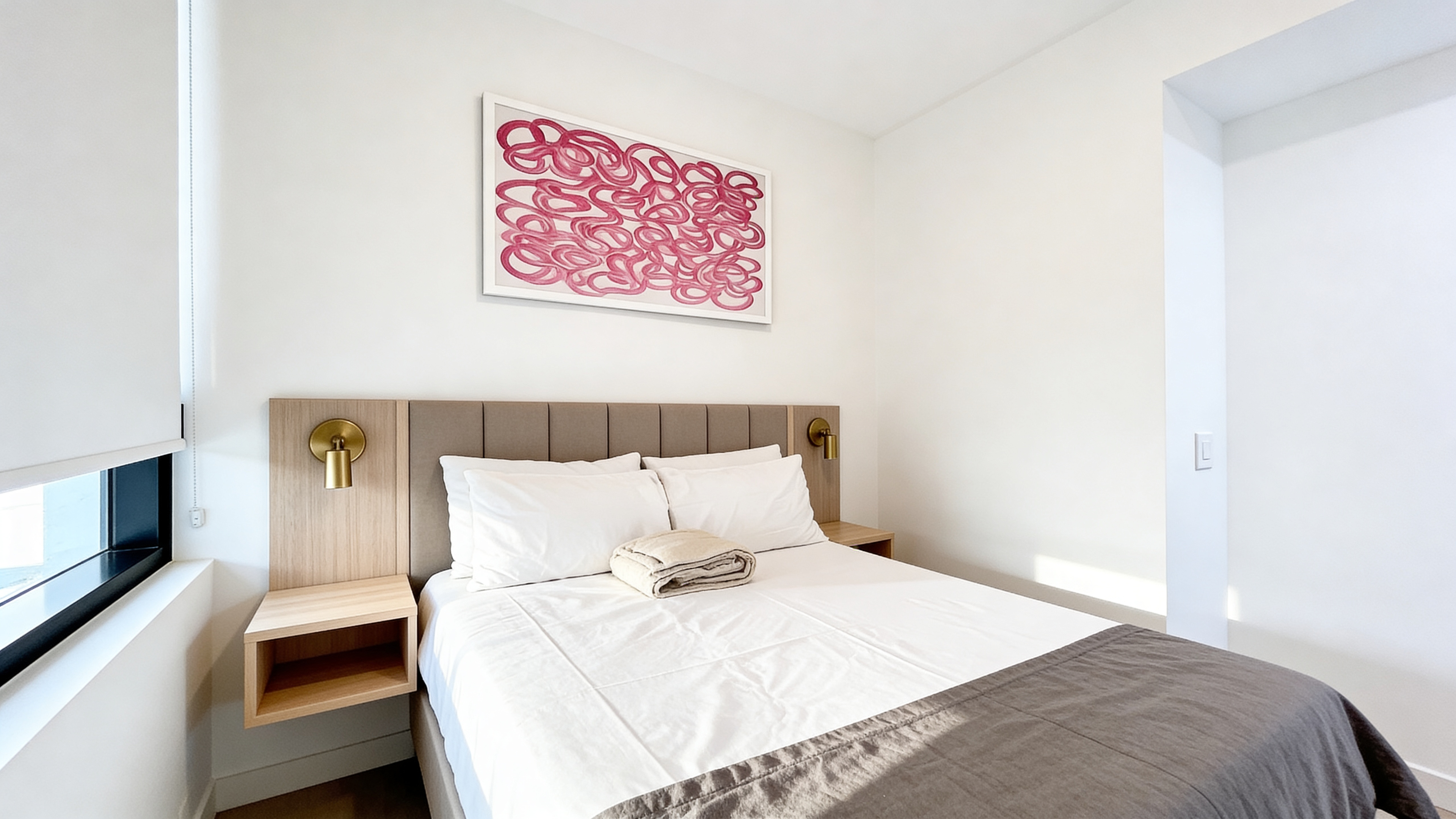 Primary bedroom — close view of headboard, gold wall sconces, and original artwork