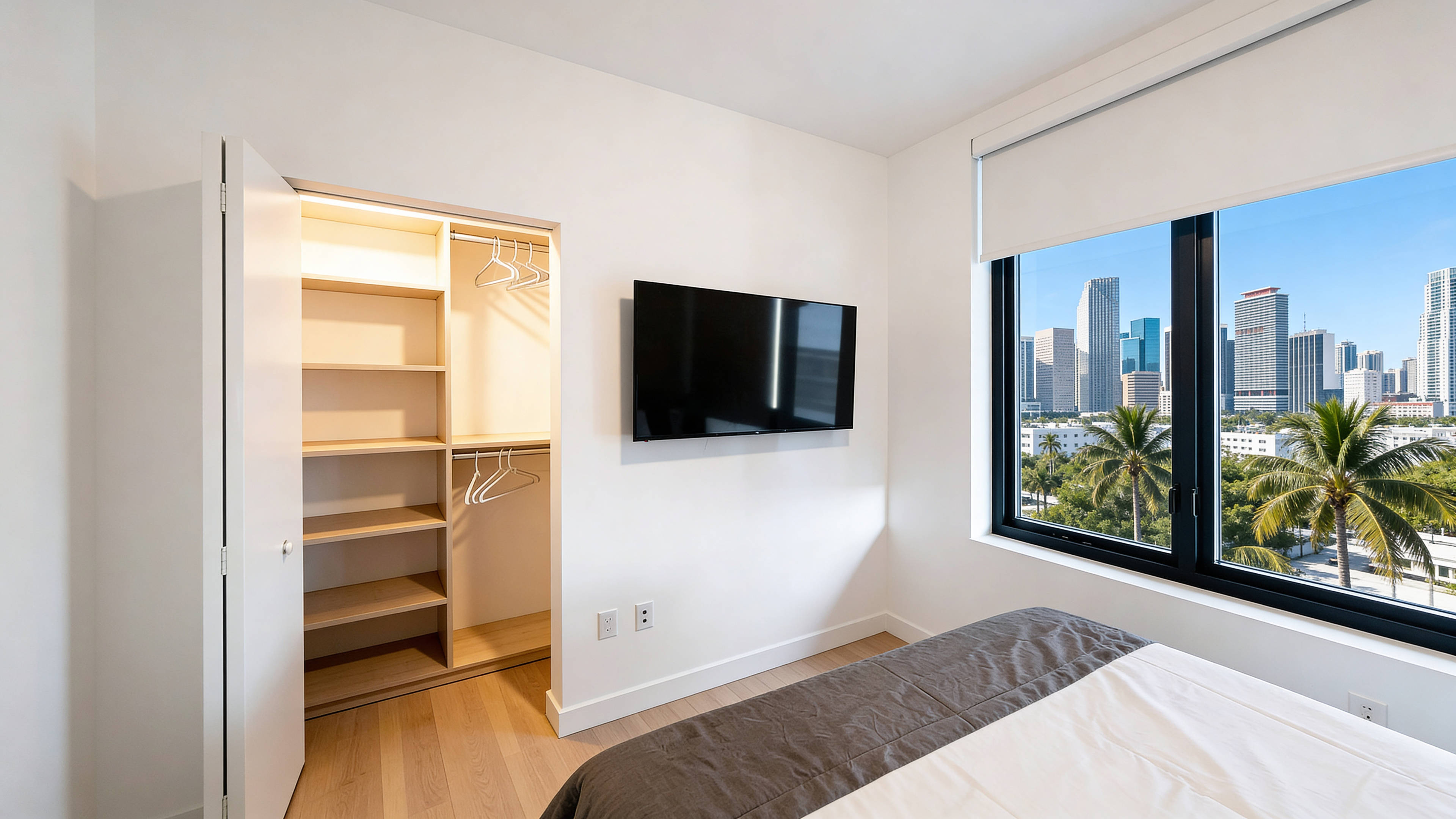 Second bedroom — built-in closet with LED accent, wall-mounted TV, palm and skyline views